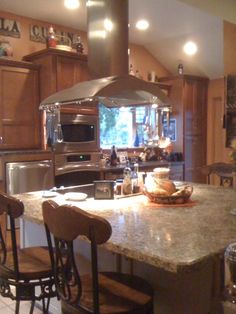 a large kitchen with an island in the middle and two stools at the counter