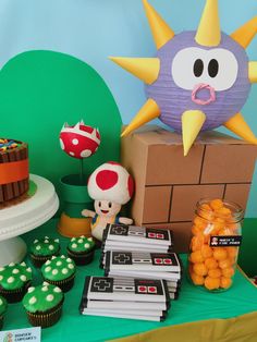 a table topped with cupcakes and cake next to a box filled with candy