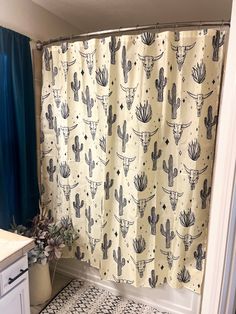 a bathroom with a cactus shower curtain and black and white floor tiles on the floor