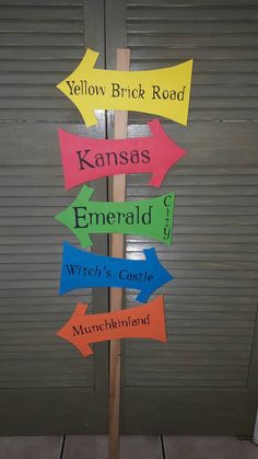 a wooden sign with many different colored arrows on it's side in front of a garage door