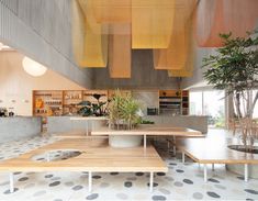 the interior of a restaurant with tables, benches and potted plants hanging from the ceiling