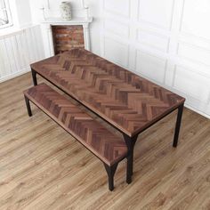 a wooden table sitting on top of a hard wood floor next to a fire place