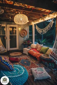 an outdoor room with lots of pillows and rugs on the floor, lights hanging from the ceiling