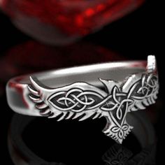 a silver ring with an intricate design on the front and side, against a black background