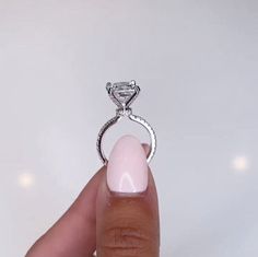 a woman's hand holding a ring with a diamond on the top and bottom