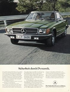 a green mercedes benz is driving down the road