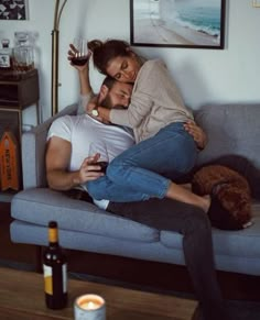 a man and woman cuddling on a couch with a teddy bear next to them