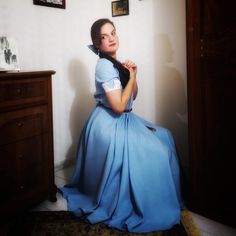 a woman in a blue dress sitting on the floor