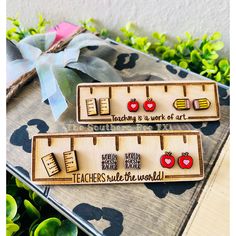 "Teacher Appreciation Earring Gift Set Each ruler includes 3 pairs of wood stud earrings and the holder, shape of a ruler. All earrings are made with hypoallergenic backings which are great for those with sensitive ears. Ruler {base} is approximately 4.5\" wide. Earrings range from .5-.6\" on the longest side. Made from 1/8\" sanded plywood. \"Teachers rule the world.\" or \"Teaching is a work of art.\" You can pick the custom option and pick the phrase that is engraved on the ruler.  Due to the natural characteristics of wood, there may be a slight difference in the stain, grain and there may be noticeable knots.  NOTICE: Colors may vary due to the different lighting and editing in the photos! -------------------------------------------------- ● Instagram - @thesouthernbeetx ● Facebook - Pencil Earrings, Teacher Earrings, Wood Stud Earrings, Apple Earrings, Wood Earrings Stud, Rule The World, Wood Studs, Earring Gift, Teacher Appreciation Gift