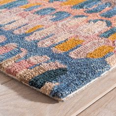 a multicolored area rug on the floor with wooden floors and wood planks