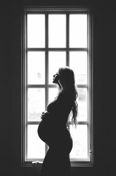 a pregnant woman standing in front of a window