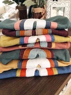 a stack of towels sitting on top of a wooden table next to a potted plant