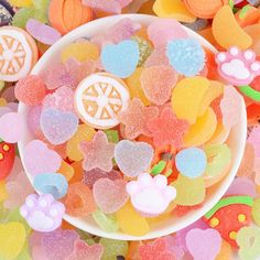 a bowl filled with gummy bears next to other candies