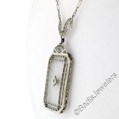 This is a gorgeous and VERY WELL MADE pendant necklace crafted during the art deco period in solid 14k white gold. It features a large, rectangular-shaped, camphor glass panel with cut corners and a stunning diamond set at its center. The pendant displays magnificent etching designs and open filigree work throughout its frame as well as the part that connects to the chain. The filigree work gives this piece its unique look and makes a special statement on this pendant. The lovely diamond is set Classic Platinum Necklaces For Evening, Antique White Gold Diamond Pendant Necklace, Vintage Diamond White Pendant Necklace, Art Deco White Gold Round Necklaces, White Gold Diamond Necklace With Filigree For Anniversary, Anniversary White Gold Diamond Necklace With Filigree, Vintage Diamond Cut Necklace In Diamond White, Vintage Diamond White Necklace With Diamond Cut, Art Deco Diamond White Necklace For Anniversary