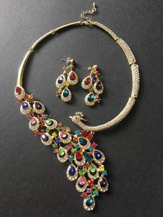 "** This necklace comes with a pair of matching earrings (studs at back design). ** Featuring detailed and lovely peacock embellished with various size and color rhinestones crystals on top and linked to cable chain. We have also added an extra long cable chain finished with a sparkle pendant at end for you to adjust the length. Just lovely and sparkling!! Color: gold decorated with assorted color rhinestone crystals Size: necklace measures around 13.25\" long and peacock tale around 6.25\" long Luxury Peacock Design Necklaces For Women, Luxury Fusion Necklace With Peacock Design, Luxury Gold Peacock Design Necklace, Luxury Wedding Chandbalis With Peacock Design, Luxury Temple Jewelry Necklace With Peacock Design, Luxury Temple Necklace With Peacock Design For Festivals, Elegant Peacock Design Jewelry Sets, Jewelry Tattoo Designs, Peacock Jewelry