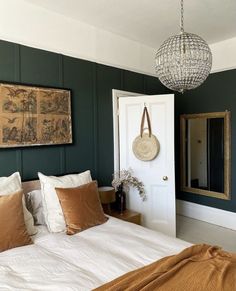 a bedroom with green walls, white bedding and brown throw pillows on the bed