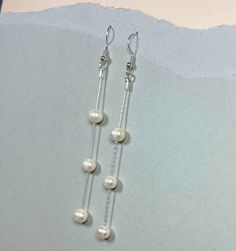 These freshwater pearl dangle drop earrings are a stunning choice for any bride or anyone who loves classic elegance. Handcrafted with sterling silver, they feature lustrous freshwater pearls that are carefully selected for their beauty and quality. The pearls dangle delicately from the silver hooks, creating a timeless and romantic look. These earrings are perfect for a wedding or any special occasion where you want to add a touch of refinement to your outfit. The long length of the earrings ad Dangly Pearl Earrings Silver, Elegant Long Drop Hypoallergenic Pearl Earrings, Elegant Hypoallergenic Long Drop Pearl Earrings, Classic White Drop Chandelier Earrings, Silver Chandelier Earrings With Pearl Charm, Pearl Dangle Linear Earrings For Pierced Ears, Classic Long Drop Pearl Earrings With Matching Pair, Sterling Silver Pearl Chain Earrings For Anniversary, Long Drop Pearl Earrings With Ear Wire