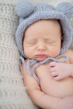 a newborn baby wearing a knitted bear hat