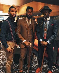 three men standing next to each other in suits and ties with one holding a cane