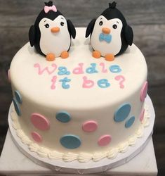 two penguins sitting on top of a white cake