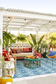 an outdoor living area with couches, tables and potted plants