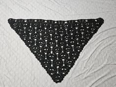 the triangle is made up of black crocheted yarn and has white dots on it