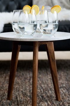 three wine glasses sitting on top of a table with lemon wedges in the middle