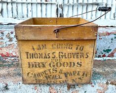 an old wooden box sitting on the side of a building that says thomas s glovyers for tax goods