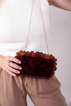 Let your personality shine through with our statement making Cava Clutch! Featuring a detachable gold chain, easily transforming it into a shoulder purse or crossbody for versatile styling options. Own the spotligth wherever you go! Acrylic 8.75"W x 5.25"H Removable Gold Chain Colors may vary with different viewing devices. Brown Chain Clutch Shoulder Bag, Party Brown Shoulder Bag With Chain, Brown Chain Shoulder Bag For Party, Chic Brown Clutch With Chain Strap, Evening Brown Shoulder Bag With Chain Detail, Chic Brown Shoulder Bag With Chain Detail, Chic Brown Shoulder Bag With Chain, Evening Brown Shoulder Bag With Chain, Trendy Brown Shoulder Bag For Party