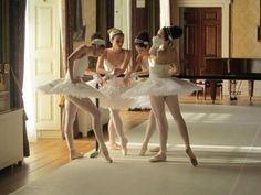 four ballerinas in white tutus posing for the camera