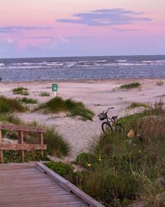 there is a bike parked on the beach next to the boardwalk and stairs that lead down to the beach