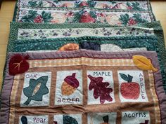 a quilted table runner with apples, maples and acorns on it