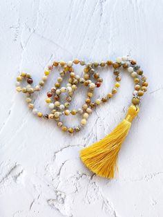 "This mala necklace is made with 108 natural stone knotted beads of yellow agate crazy lace adorned with silver beads. This prayer garland  is the perfect support garland for counting mantras during your practices. This is a very light weight, a spiritual sacred jewelry for chakra healing. I make each mala by hand, knotting each of the 108 beads with great care and I made every single silky and delicate tassel. I use a very resistant braided macrame rope, achieving a mala that lasts over time. All our malas are very versatile, since you can use them on many occasions. This prayer garland has two beads size:  - small 6mm.   50 cm / 20 inch - large 8mm.  62 cm / 24 inch Spiritual Stone jewels choose personally every single gemstone for her prayer garlands, to ensure his beauty and quality. Braided Macrame, Sacred Jewelry, Yellow Agate, Statement Collar, Yellow Gemstones, 108 Bead, Mala Necklace, Crazy Lace Agate, Chakra Healing