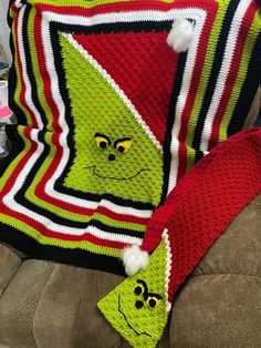 a crocheted grin face blanket and pillow on a couch with two matching throw pillows