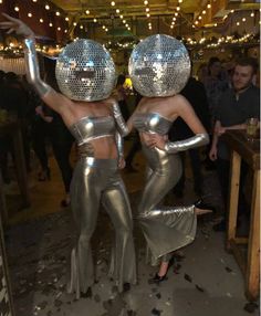 two women in silver disco outfits dancing at a party