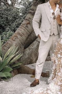 a man and woman standing next to each other in front of a tree with white flowers on it