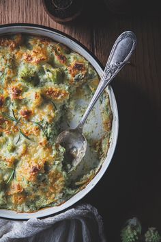 a casserole dish with broccoli and cheese in it on a wooden table