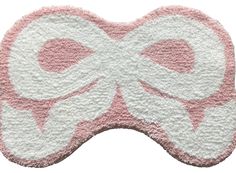 a pink and white bow shaped rug on top of a white surface with the word love written