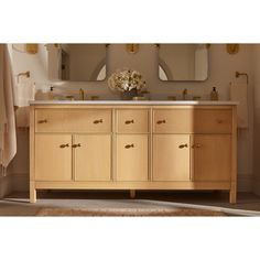 a bathroom with two sinks and mirrors on the wall next to a rug in front of it