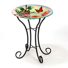 a glass table with wrought iron legs and a butterfly design on the top, against a white background