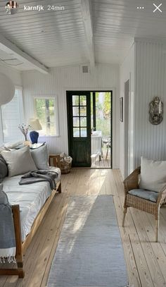 a living room with white walls and wooden floors, two couches and a rug on the floor