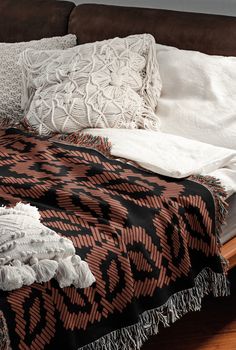 a bed with pillows and blankets on top of it next to a wooden headboard