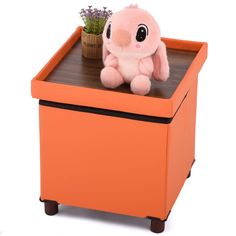 a stuffed animal sitting on top of an orange box with a potted plant in it