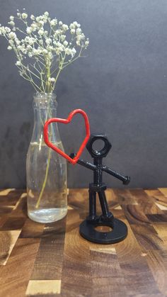 a vase filled with flowers and a small black figure holding a red heart in it