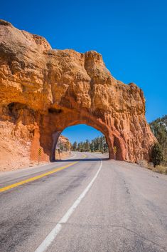 an arch shaped rock formation on the side of a road