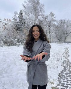 a woman standing in the snow with her hands out