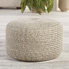 a large white round poufce sitting on top of a rug next to a potted plant