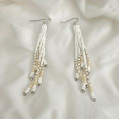 Crafted with meticulous attention to detail, these White and Cream Fringe Earrings are an exquisite blend of creativity and elegance. The cream fringe dances playfully, adding a touch of bohemian charm that is perfect for any festival or special occasion. Handmade with Creative Beadwork, these earrings are a true testament to artisanal craftsmanship. Perfect for gifting, these Seed Bead Fringe Earrings are a beautiful option for Mother's Day or any celebration. The delicate seed beads intertwine White Faceted Beads Beaded Earrings Gift, White Faceted Beaded Earrings As A Gift, White Dangle Earrings With Faceted Beads, Adjustable White Beaded Necklace With Dangling Beads, Elegant White Dangling Beads, White Beaded Necklaces With Dangling Beads, White Beaded Earrings With Round Tiny Beads, White Beaded Earrings With Faceted Round Beads, White Dangling Beads For Jewelry Making