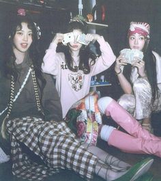 three young women sitting next to each other on the floor holding cards in their hands