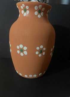 a brown vase with white flowers painted on it